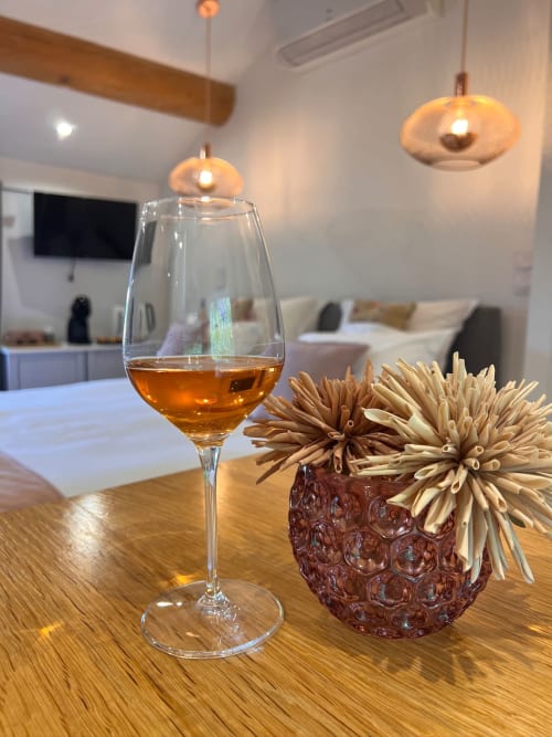 Élégant verre de vin ambré et arrangement de fleurs séchées sur table en bois à La Maison de Vaison boutique hôtel