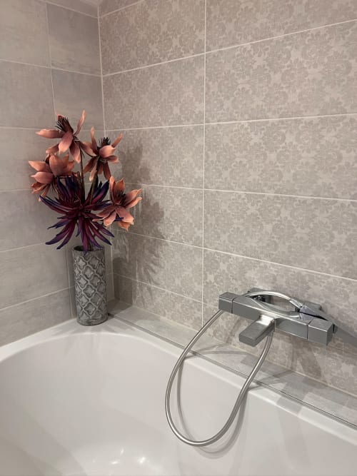 Salle de bain moderne à La Maison de Vaison B&B avec baignoire, carrelage, robinetterie chrome et fleurs corail