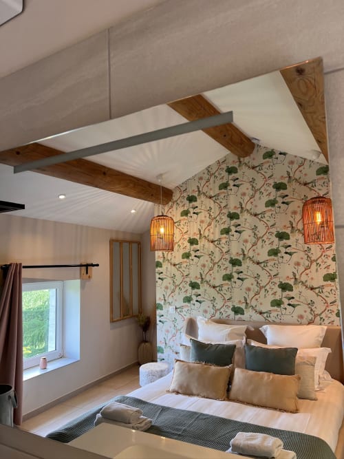 Chambre élégante à La Maison de Vaison avec papier peint botanique, poutres en bois et luminaires orange