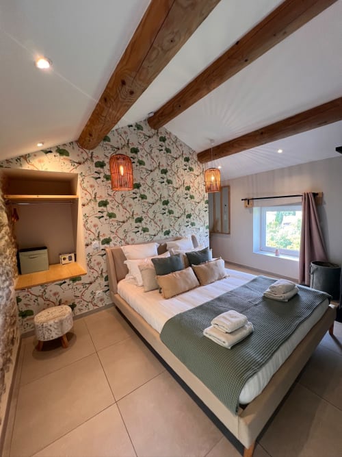 Chambre luxueuse à La Maison de Vaison avec poutres apparentes, papier peint fleuri et équipements modernes