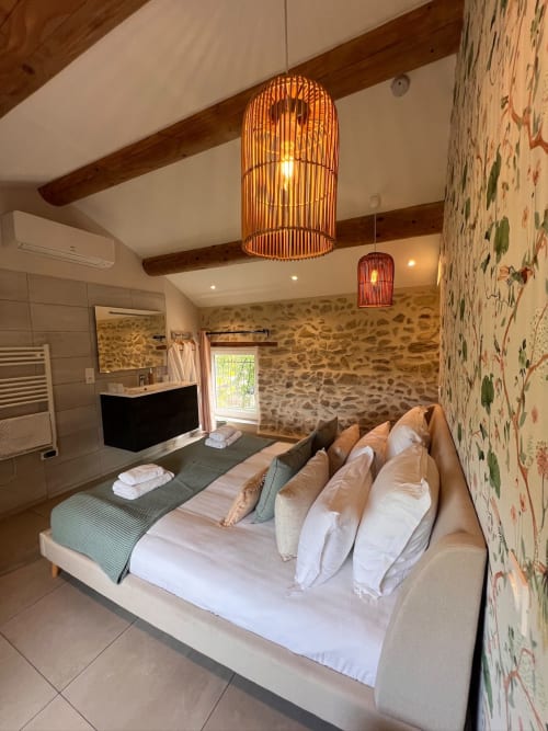 Chambre de luxe à La Maison de Vaison avec murs en pierre, luminaires suspendus modernes et salle de bain attenante à Vaison-la-Romaine