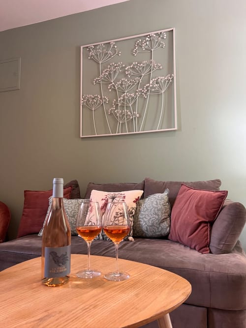 Élégant salon de La Maison de Vaison avec rosé et verres sur table en bois, canapé gris aux coussins roses