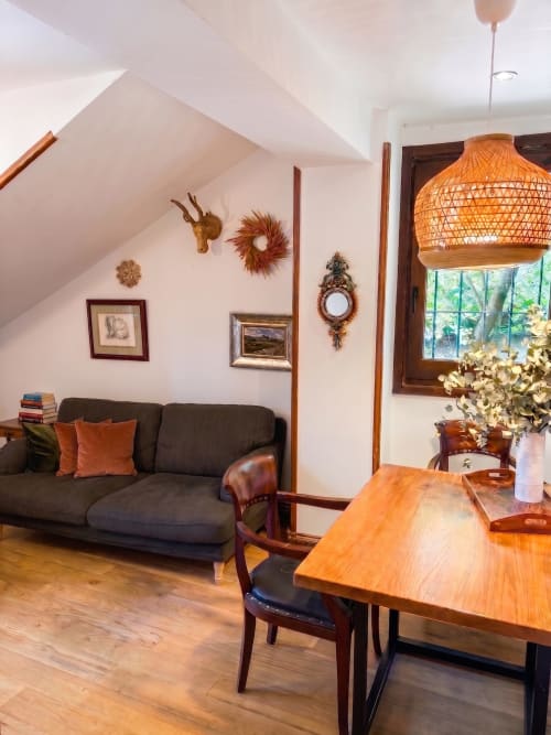 Acogedora sala de estar en El Aserradero con sofá, mesa de comedor, detalles de madera y vistas al jardín en La Alberca