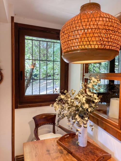 Elegante comedor en El Aserradero con lámpara de tejido, mesa de madera, arreglo de eucalipto y vistas al jardín