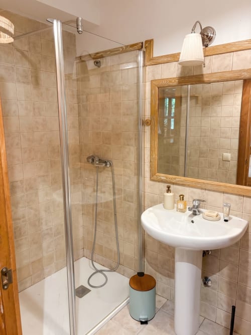 Baño moderno en apartamento Encina de El Aserradero, La Alberca, con ducha, lavamanos pedestal, espejo con marco de madera y tonos beige