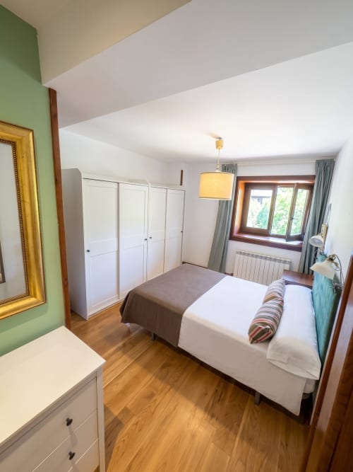 Luminoso dormitorio en El Aserradero de La Alberca con armarios blancos, suelos de madera y vistas al jardín