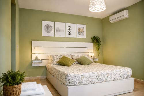 Camera luminosa verde brillante a Castelli Apartments a Castel Gandolfo con letto bianco, testata moderna, cuscini decorativi e vista su Roma