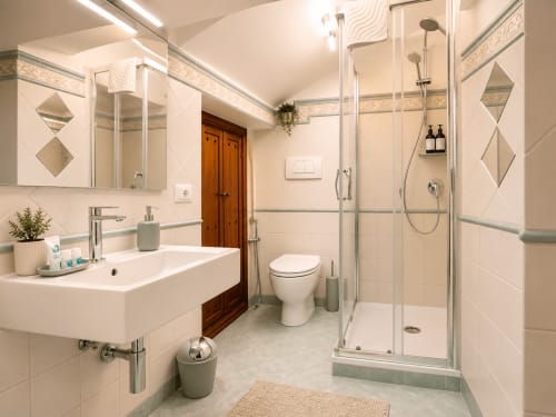 Moderno bagno con doccia in vetro, lavabo bianco, wc e porta in legno presso Castelli Apartments a Castel Gandolfo