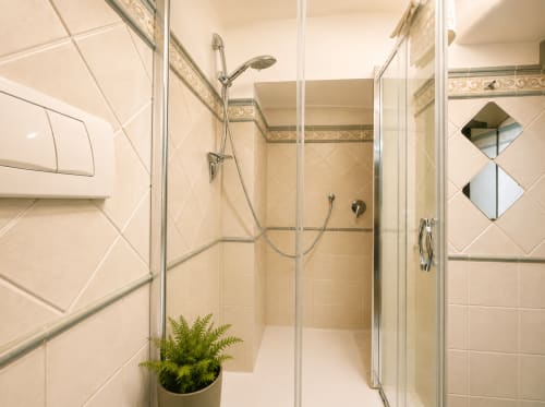 Moderna doccia con box in vetro nell'appartamento Castrum Home a Castel Gandolfo, con piastrelle bianche e fascia decorativa