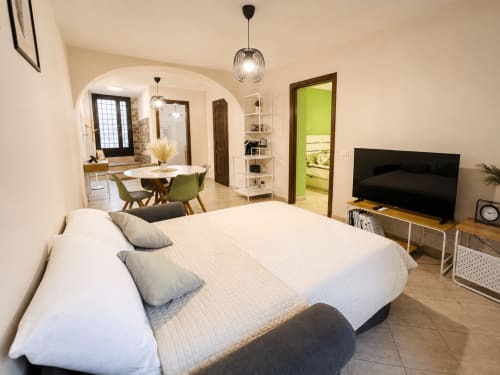 Camera da letto di monolocale moderno con letto bianco, TV a schermo piatto, zona pranzo e porta del bagno verde brillante a Castelli