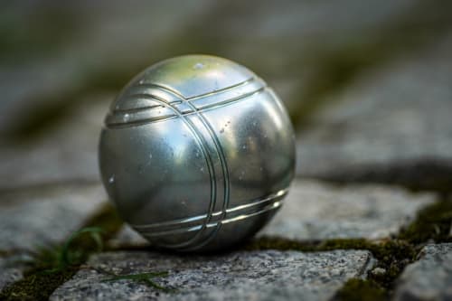 Bola de petanca de metal sobre terreno cubierto de musgo en Yasi Hostel Lyon, actividad recreativa al aire libre