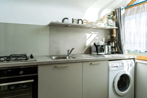 Modern kitchenette at Ferme de Kervihern guesthouse with gas stove, sink, washing machine, and stainless steel appliances in