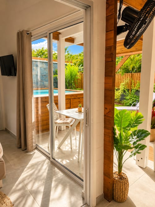 Patio privé du Filao Cottage avec portes coulissantes, table à manger, vue sur jardin tropical et accès piscine à Sainte-Rose