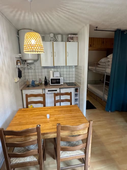 Petit coin cuisine accueillant avec table à manger et lits superposés à la résidence GNM Edelweiss à Vars, France
