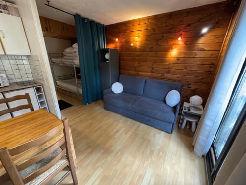 Appartement 4 chambres cosy à la résidence GNM Edelweiss à Vars avec murs en bois, canapé bleu et lits superposés