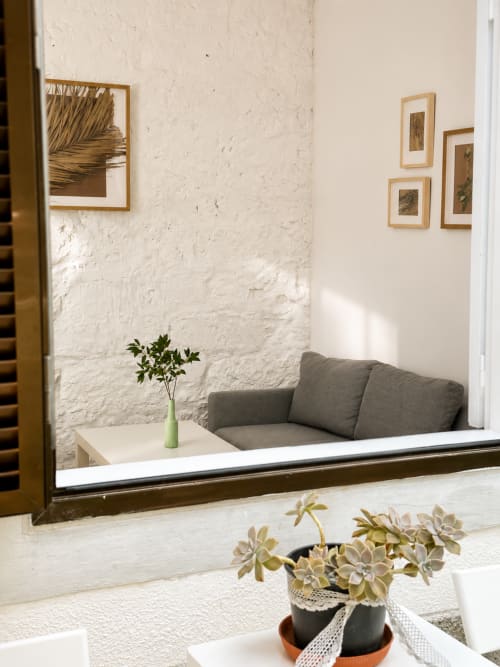 Alcova aconchegante em Villas Simone com sofá cinza, paredes de tijolo branco, arte botânica e exibição de plantas suculentas