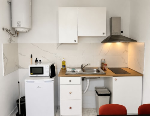 Kitchenette moderna e compacta em Villas Simone Porto Santo com armários brancos, painel de mármore e aço inoxidável