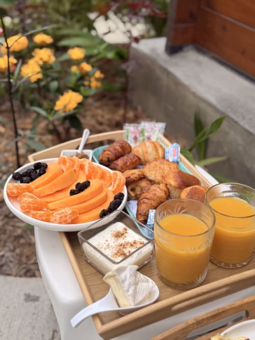 Plateau petit-déjeuner à la Filao Cottage avec croissants, fruits frais, jus et yaourt dans le jardin