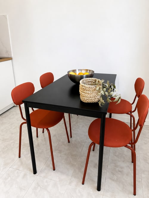 Sala de jantar moderna com mesa preta e quatro cadeiras vermelho-ferrugem em Villas Simone Porto Santo