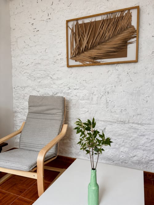 Quarto minimalista moderno nas Villas Simone Porto Santo com poltrona de madeira, parede de tijolos brancos, arte botânica e ambiente fresco