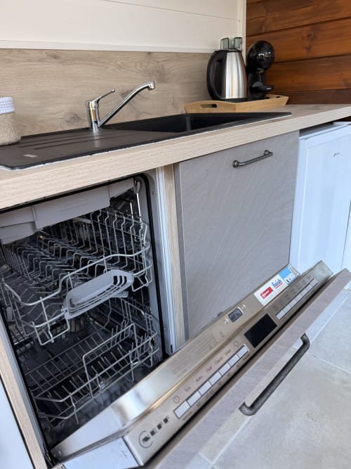 Évier de cuisine moderne avec robinetterie, plan de travail noir et lave-vaisselle en acier inoxydable au Gîte Filao à Sainte-Rose, Guadeloupe