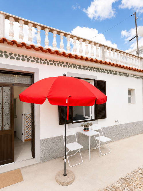 Guarda-chuva vermelho e cadeiras brancas no pátio da Casa da Anita nas Villas Simone Porto Santo, Portugal