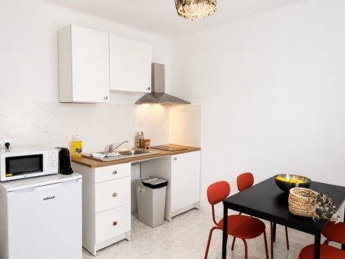 Cozinha e sala de jantar modernas em Casa da Anita, Villas Simone Porto Santo com armários brancos, bancadas de madeira e cadeiras vermelhas