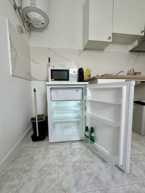 Refrigerador aberto na cozinha do apartamento de Porto Santo com micro-ondas e eletrodomésticos visíveis no balcão