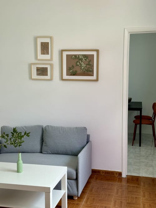 Sala de estar moderna em Villas Simone Porto Santo com sofá cinza, mesa branca, arte botânica na parede e piso de madeira