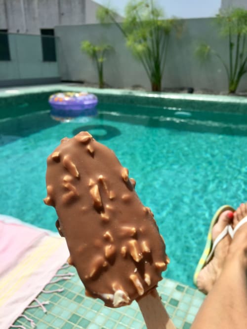 Sorvete de chocolate à beira da piscina no Villas Simone Funchal, com piscina de água turquesa e terraço ao fundo