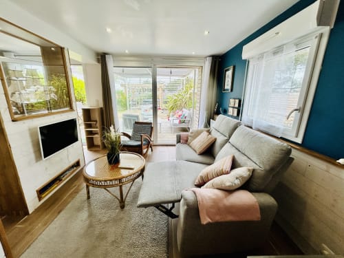 Helles modernes Wohnzimmer der Villa Plein Vent B&B in Barneville-Carteret mit grauem Sofa, Terrassenzugang und Akzenten in Blaugrün