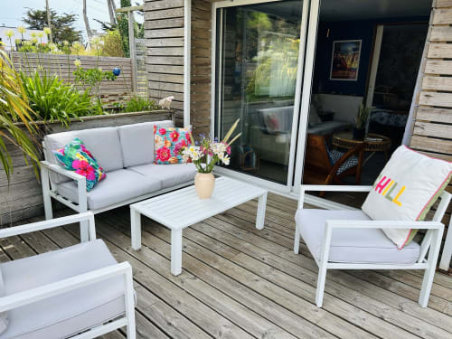 Farbenfrohe Außenterrasse der La Villa Plein Vent, Barneville-Carteret, mit weißen Möbeln, bunten Kissen und Meerblick