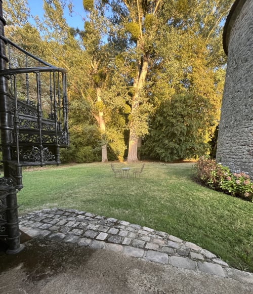 Jardin du Colombier de Hanches avec pelouse soignée, grands arbres, murs en pierre et portail orné en France