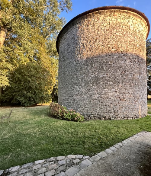 Tour de pierre historique au toit conique, entourée de pelouse verdoyante et d'arbres au Colombier de Hanches, Hanches, France