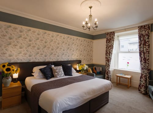 Superior King bedroom at Douglas House B&B, Castle Douglas, with floral wallpaper, dark headboard, and burgundy curtains