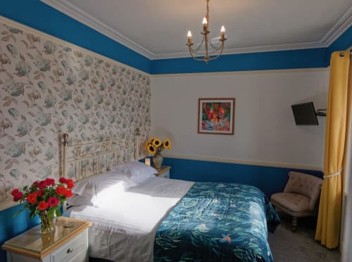 Deluxe King bedroom at Douglas House B&B with blue walls, floral wallpaper headboard, sunflowers, red roses, and yellow
