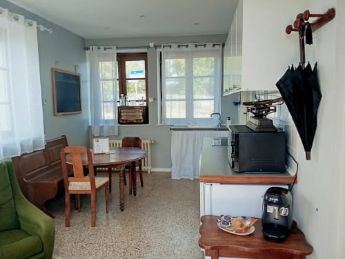 Spacieux séjour à Chez Mary Studios Gannat avec table à manger, cuisine, canapé, baies vitrées et vue sur le jardin