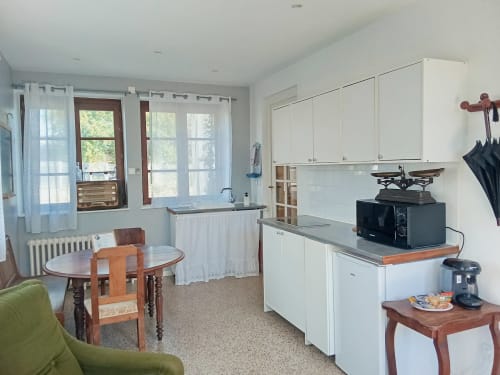Cuisine et salle à manger de l'appartement Romance chez Sir Guillaume aux Studios Chez Mary Gannat avec meubles blancs et jardin