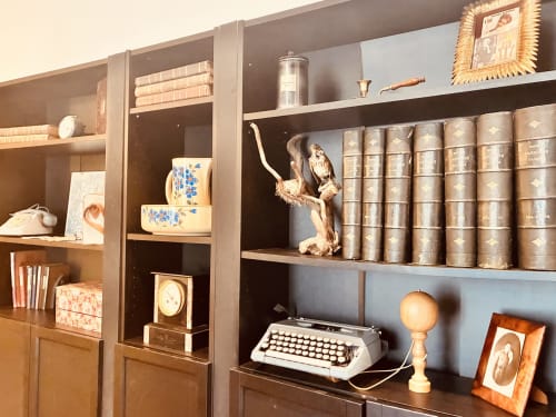 Élégante bibliothèque intégrée avec livres vintage, machine à écrire, objets de décoration et photos encadrées chez Chez Mary Studios Gannat
