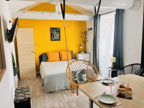 Chambre studio jaune vif avec chaise suspendue, coin repas et poutres blanches à Gannat, France