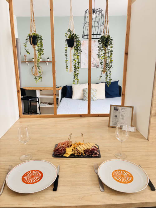Mise en place intime aux Studios Chez Mary à Gannat : assiettes, verres de vin, charcuterie et plantes suspendues.
