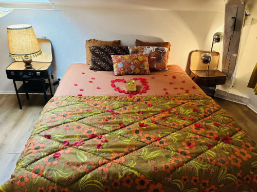Retro 70s-themed bedroom at Chez Mary Studios Gannat with flower-patterned bedding, pink rose petals, and vintage furnishings