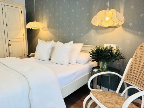 Dormitorio moderno con ropa de cama blanca, lámparas colgantes de diseño y silla de ratán en Sinese Design Homes, frente de playa de Málaga