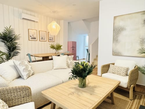 Luminoso salón costero con sofá crema, mesa de madera y balcón con vistas al mar en dúplex frente al mar de Málaga