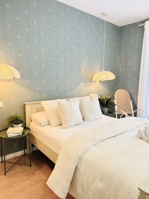 Luminoso dormitorio con papel pintado de copos de nieve verde salvia, ropa de cama blanca, lámparas colgantes y vistas al mar en Sinese Design Homes Málaga
