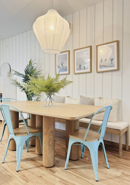 Comedor moderno en dúplex frente al mar en Málaga con mesa de madera, sillas azules, plantas en maceta e iluminación colgante