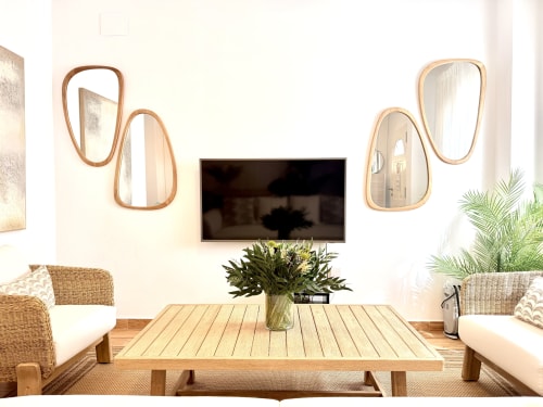 Salón moderno con televisión, muebles de madera, espejos tejidos y flores frescas con vistas a la playa de Málaga