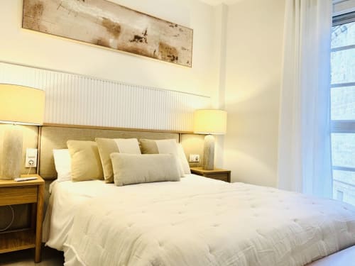 Dormitorio luminoso en apartamento Cathedral Deluxe, centro histórico de Málaga, con cama queen, lámparas amarillas y vistas a monumentos