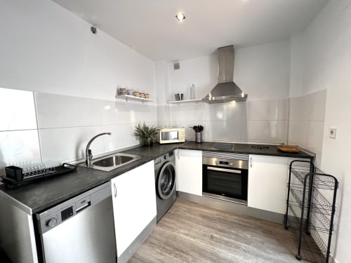 Cocina moderna en apartamento Cathedral Deluxe, centro histórico de Málaga, con muebles blancos, encimeras negras y acero inoxidable
