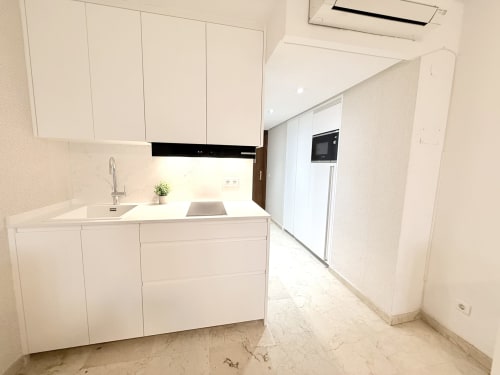Cocina blanca moderna con piso de mármol en apartamento de Torremolinos, Sinese Design Homes